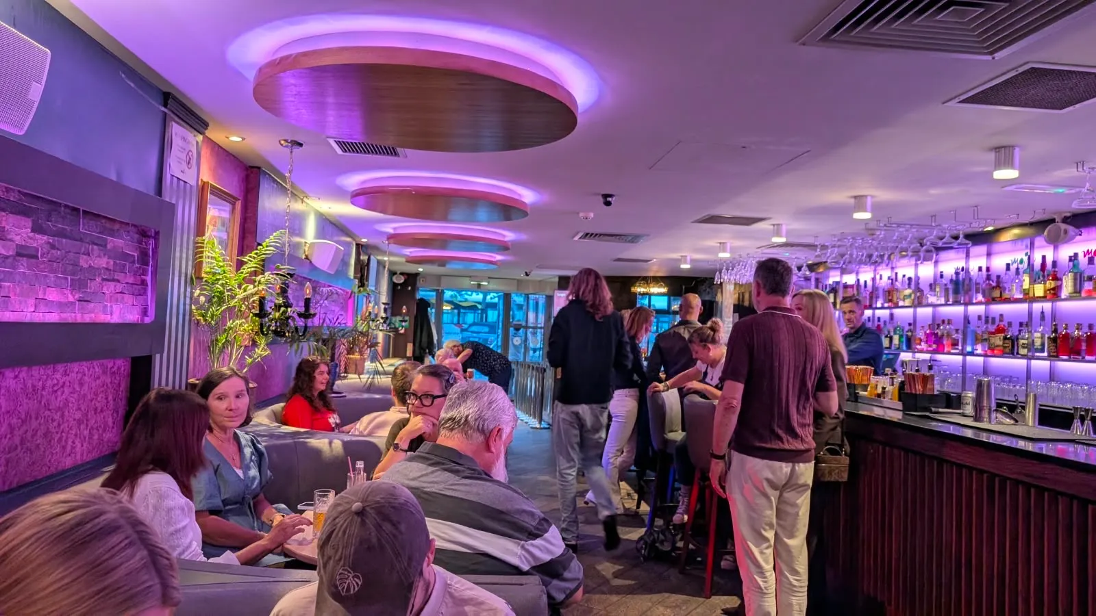 People standing and sitting with drinks at the bar before the talks