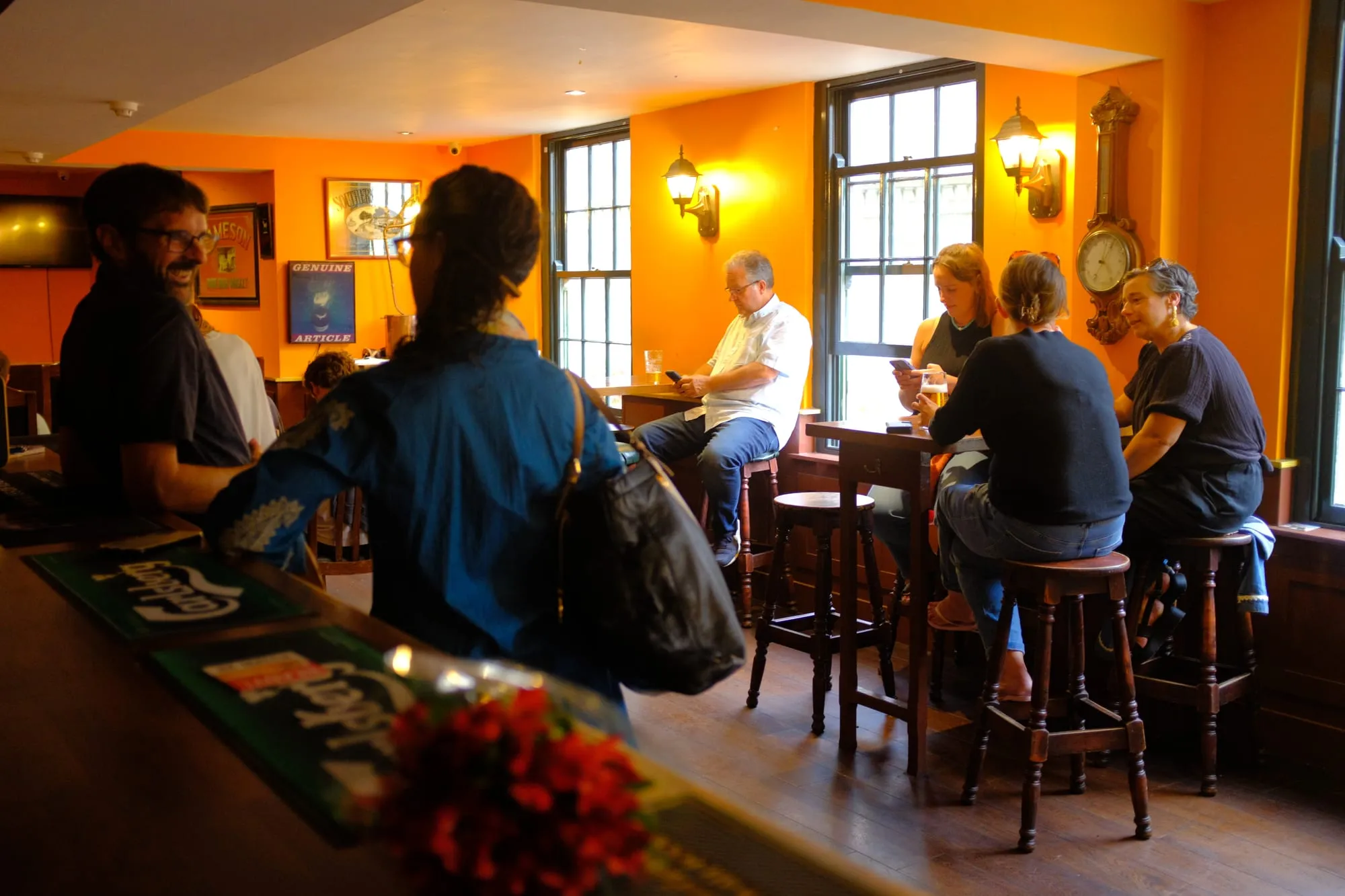 People gathered at the bar with pints, chatting at high tables
