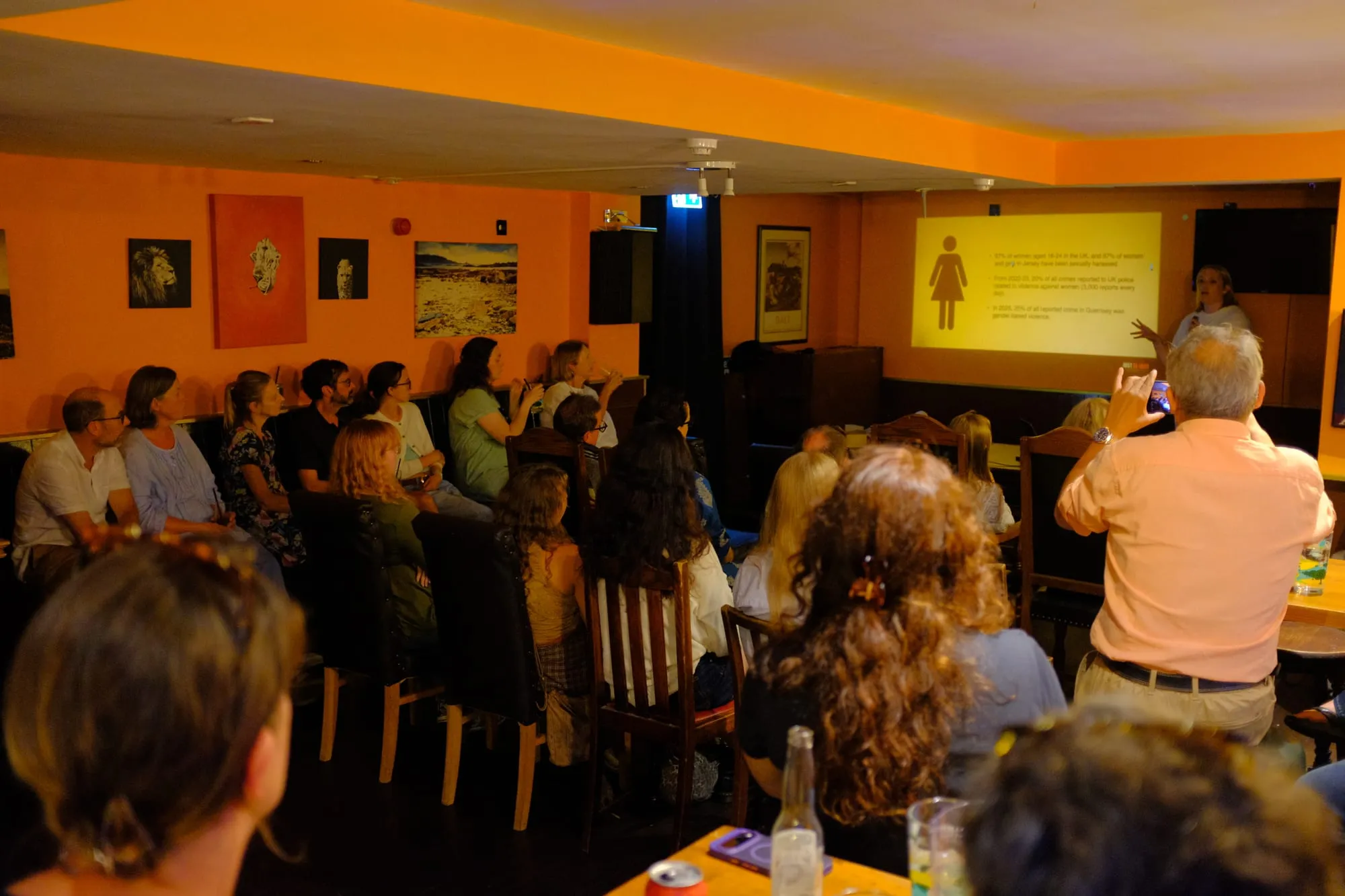 Poppy Murray presenting to a full room, her slides projected on the wall
